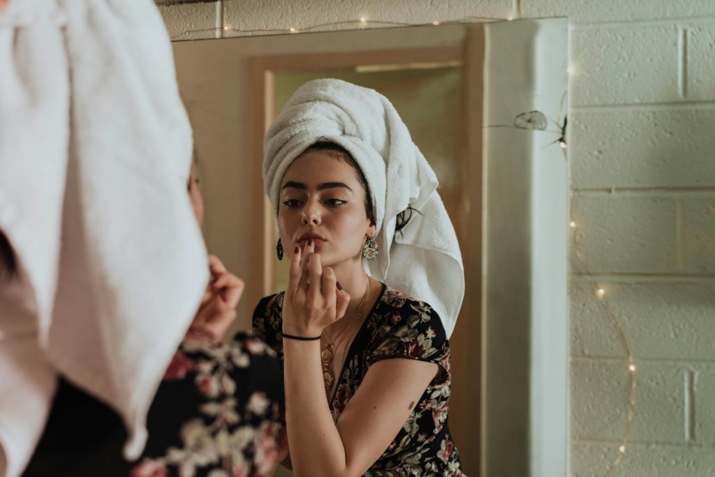 woman putting makeup in front of mirror